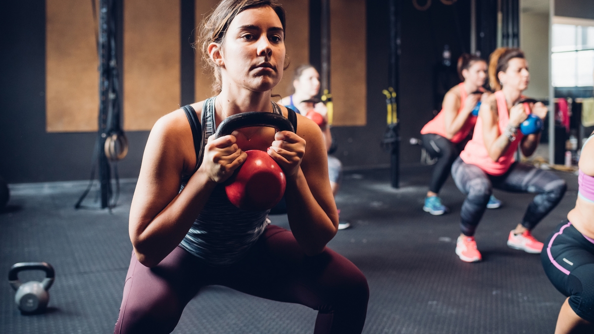 exercises, Women training in gym, squatting and lifting kettle bells