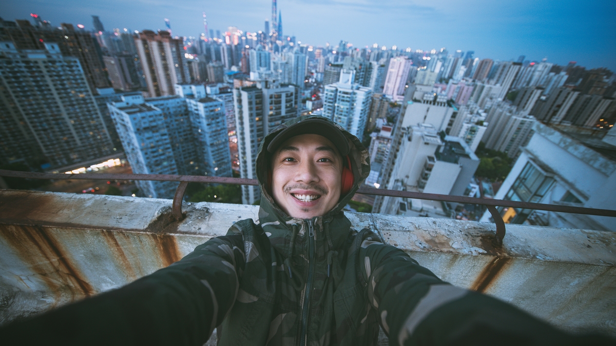 meeting meetways Selfie portrait of man using headphones and looking at camera with smile on rooftop of tall building, Shanghai, China