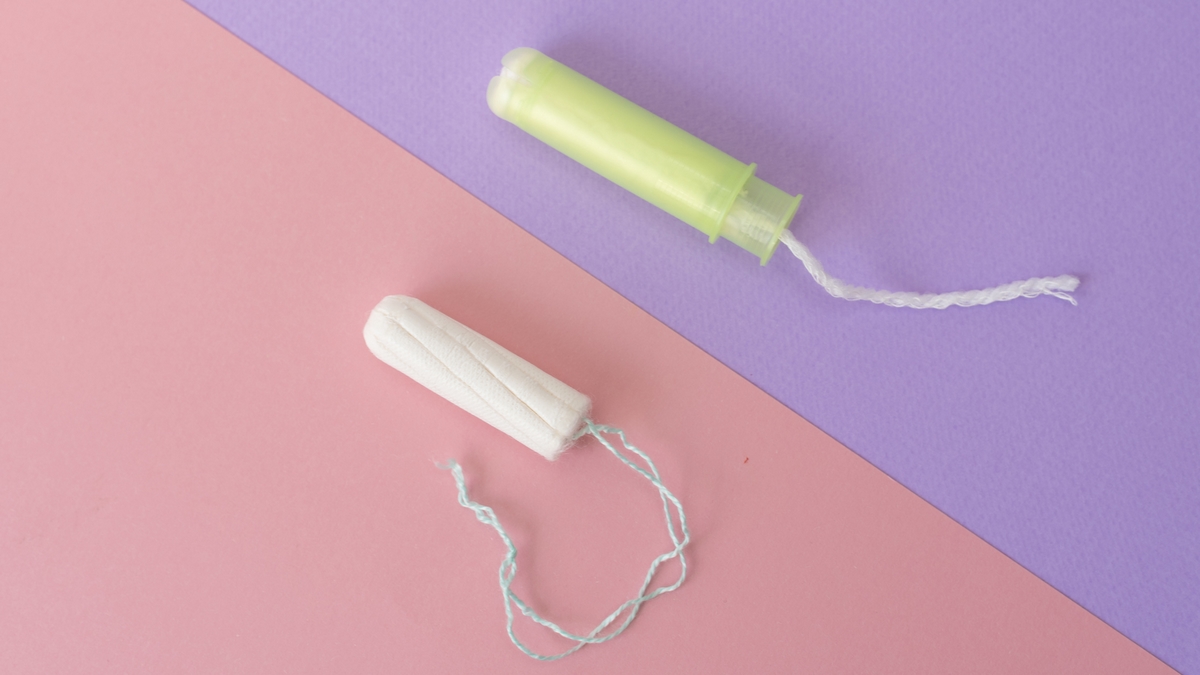 Two cotton tampons with light green applicator and without applicator on a pink and violet background. Hygienic types of tampons. Menstruation, protection, comparison concept, flat lay, Copy space, top view