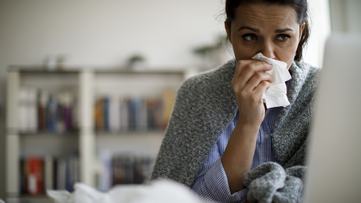 symptoms coronavirus Woman blowing her runny nose