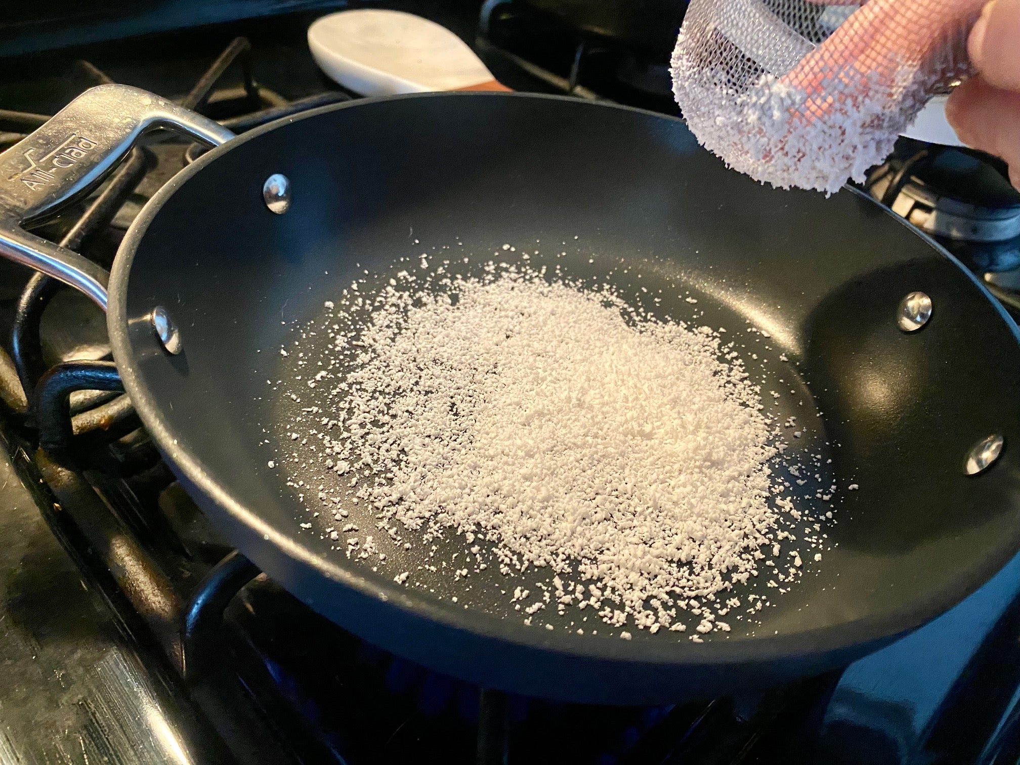 Sieving tapioca into a hot pan. (Photo: Allie Chanthorn Reinmann)