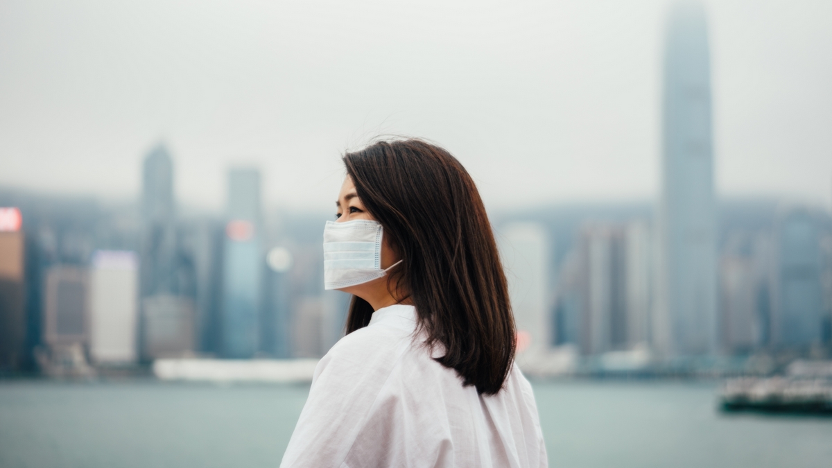 Young asian woman wearing protective face mask in city due to the polluted air