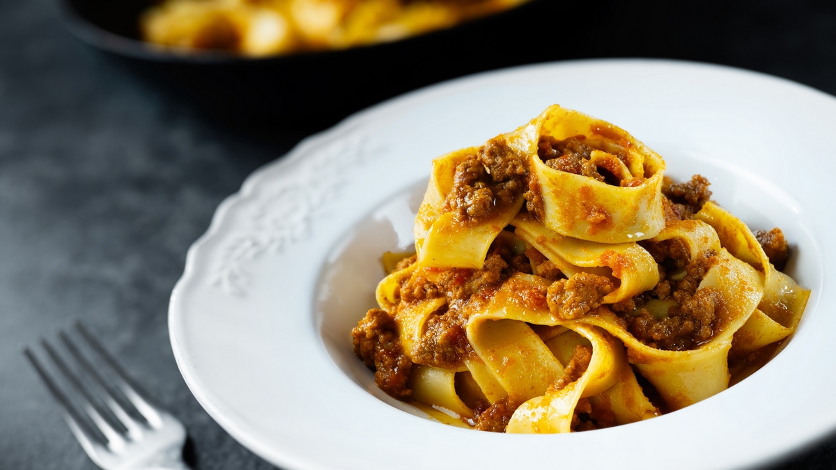closeup of rustic italian pappardelle pasta bolognese in meat sauce